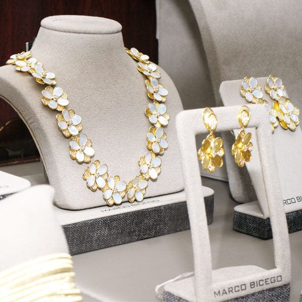 Gold and white Marco Bicego floral necklace on a mannequin bust with matching earrings displayed.