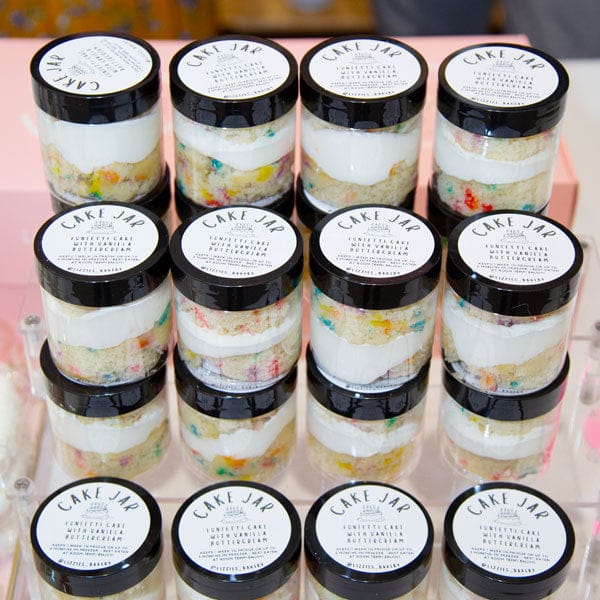 Multiple jars of Cake Jar dessert on a pink surface