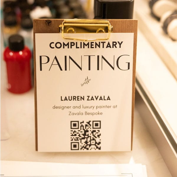 Complimentary painting sign with Lauren Zavala's name and a QR code on a clipboard.