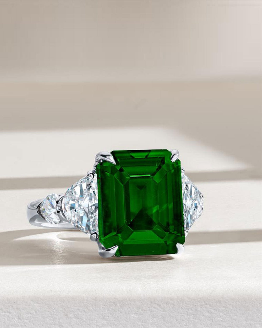Ring with a large green gemstone and diamond accents on a light background