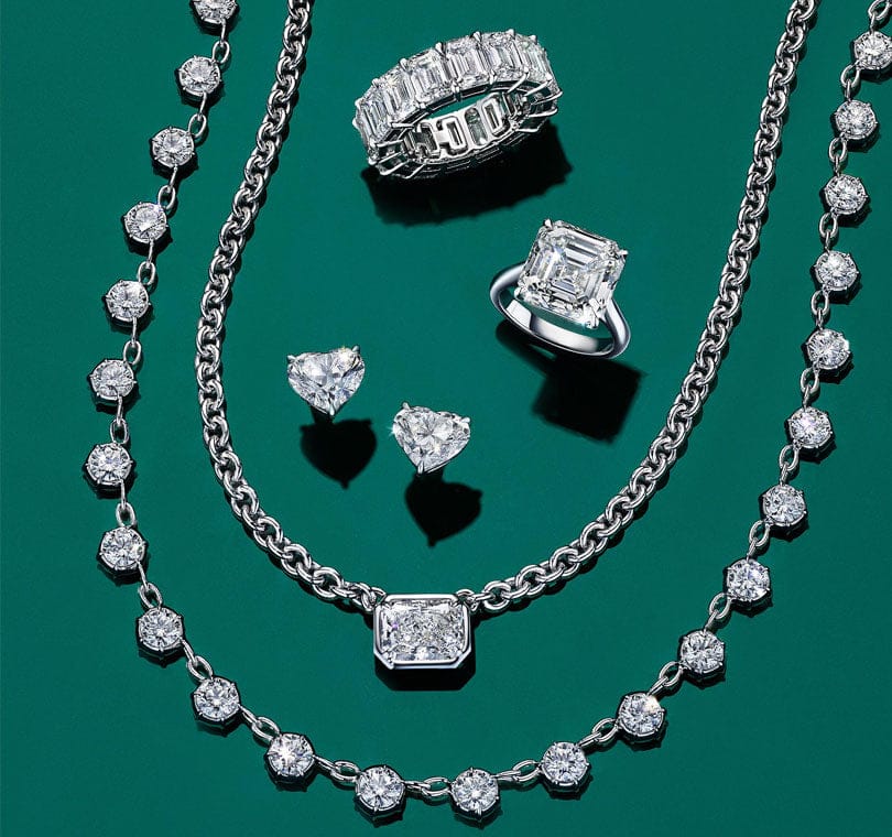 diamond jewelry including rings, earrings and necklaces on a green background