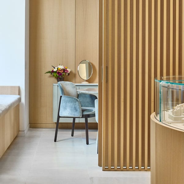 Long's Jewelers Boston, showing a modern interior with wooden slat wall, chair, and round mirror.