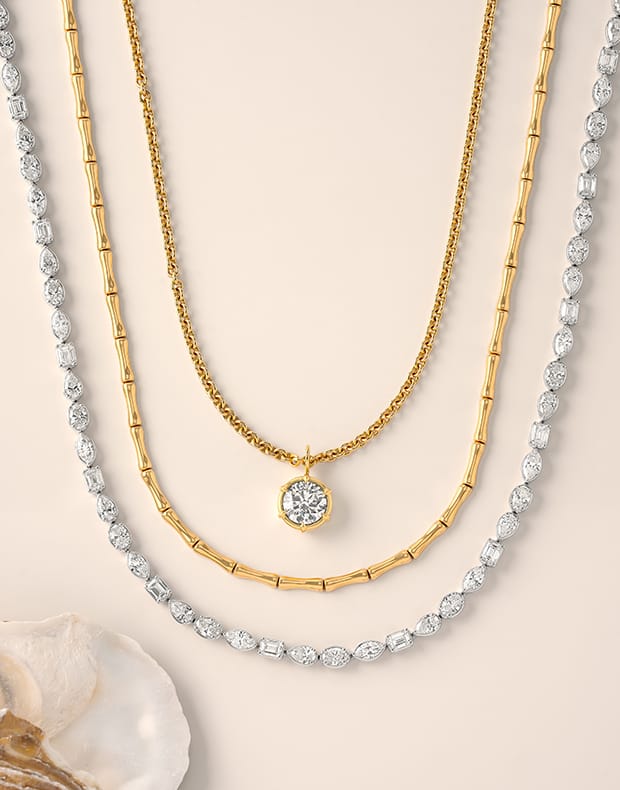 Three necklaces with diamonds on a beige background and a shell