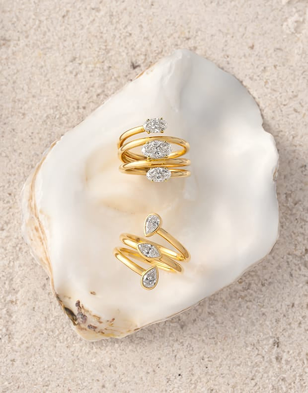 Gold rings with gemstones on a seashell against a sandy background
