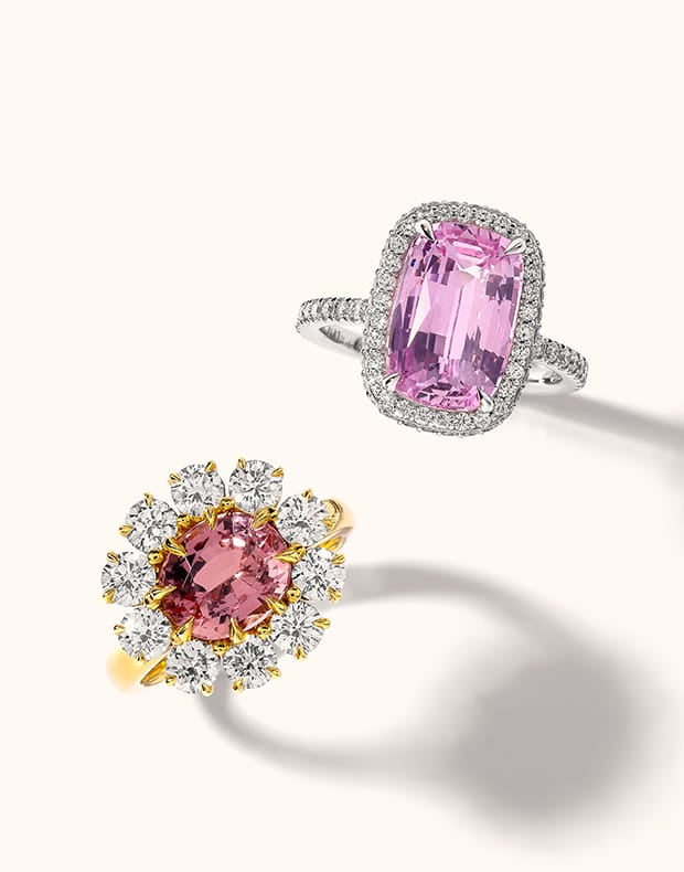 Two rings on a clean off-white background: one silver ring with a large rectangular pink gemstone in a halo setting, and one yellow gold ring with a round pink gemstone surrounded by clear stones.