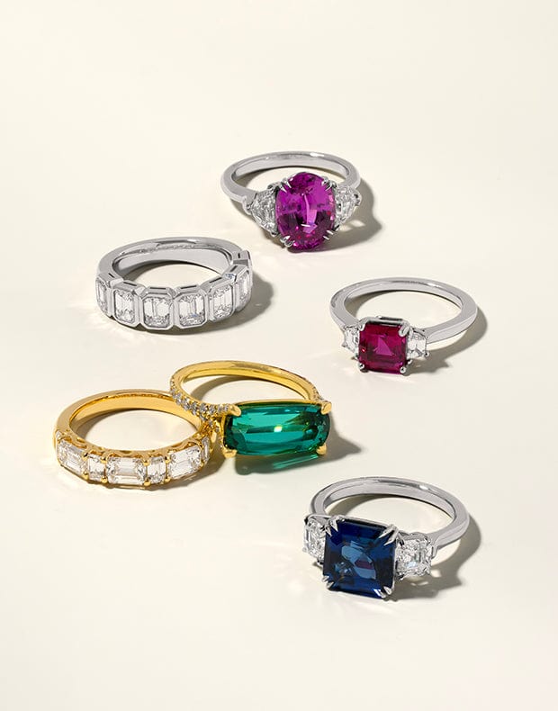 Collection of colorful gemstone rings on a light background