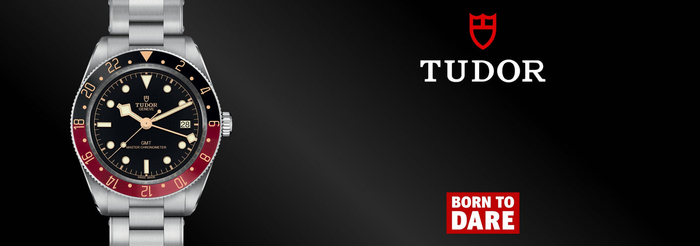 Tudor watch with black face and red accents on a dark background, featuring the Tudor logo.