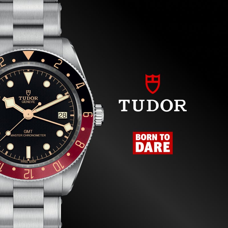 Tudor watch with black and red face on a dark background, featuring the Tudor logo.