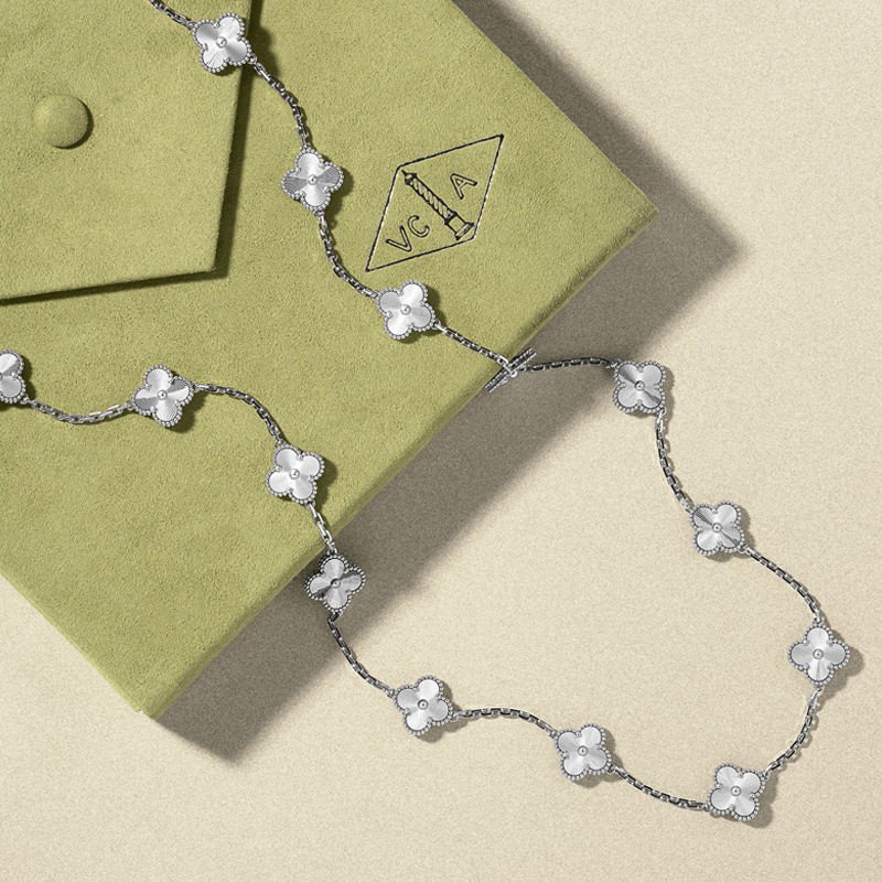 Silver Alhambra necklace on a green jewelry box with 'VCA' branding. Vintage and estate jewelry.