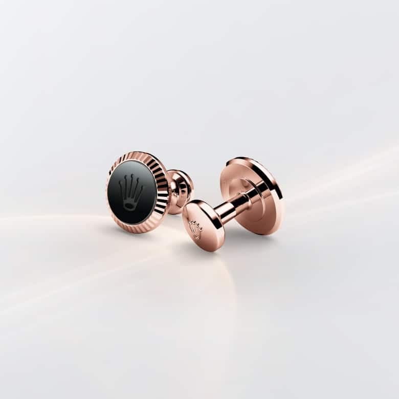 Rose gold cufflinks with a black center on a light gray background