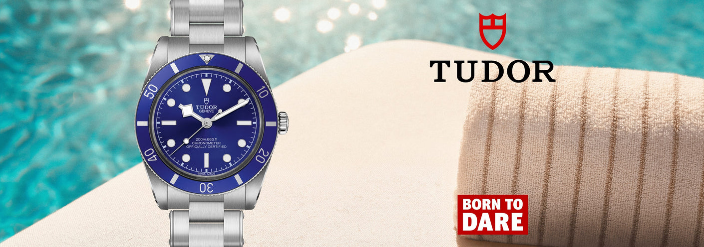 A Tudor watch with a blue dial and silver metal bracelet, shown against a poolside background with a towel and the Tudor logo and 'Born to Dare' badge.