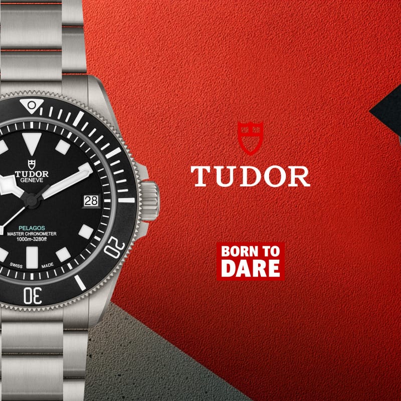 Tudor watch with black dial and silver bracelet on a red background with Tudor logo.